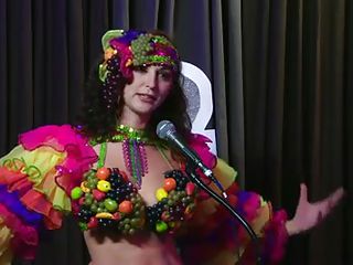 The hosts of Playboy Radio's Morning Show are looking at their guest model who is wearing the suit she'll be wearing to the Playboy Mansion for Halloween. Her head and tits are covered in fake fruit like oranges, limes, lemons, and more. She flashes her breasts for the hosts and viewers.